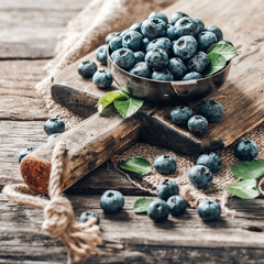 Freshly picked blueberries in bowl on wooden background. Healthy eating and nutrition.