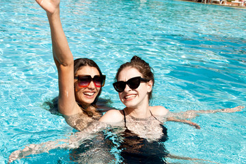 Beautiful girls in swimsuits having fun in the pool. Summer concept.