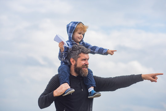 Happy fathers day. Dad and son are playing on sky background. Father and son building together a paper airplane. Portrait of happy father giving son piggyback ride on his shoulders and looking up
