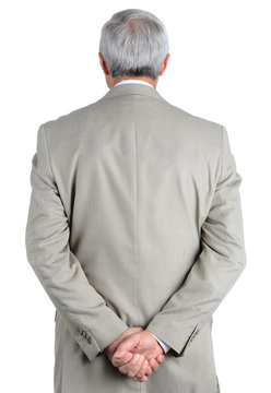 Closeup of a mature, businessman seen from behind with his hands clasped behind his back.