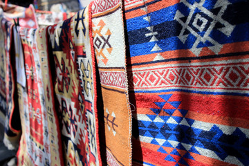 Hand-made carpets hanging in street market.