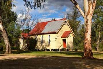Old wooden country church between two large trees.