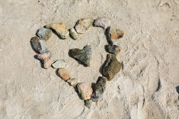 close up heart shaped stones on sandy beach