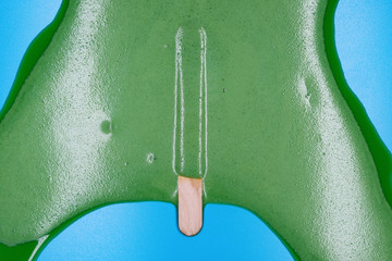 green popsicle melted on blue background