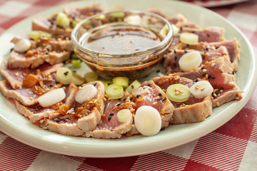 Plated Ahi tuna as an appetizer, sliced and garnished with onion