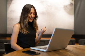 Business woman work process concept. Young woman working university project with generic design laptop. Happy excited woman at home workstation. Blurred background, film effect.