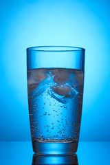 Glass of water on blue background