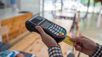 Young man using payment terminal machine.