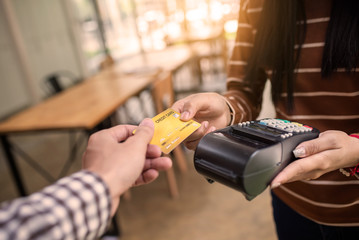 Young man customer making wireless or contactless payment using credit card.
