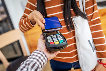 Close up hand paying order by credit card on payment terminal.
