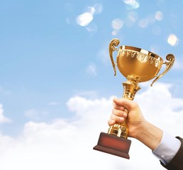 Hand holding golden trophy on blurred background