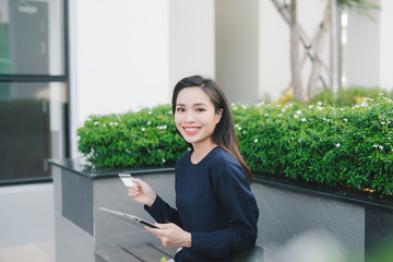 A pretty young asian business woman on bench outside office building