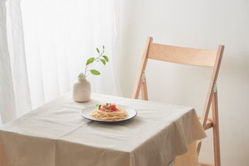 handmade pasta with ragout sauce on plate on vintage white table with colander and flowers