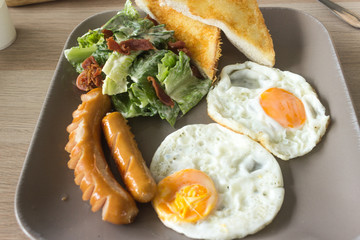 Set of american breakfast with fried eggs and sausage on wood table background.