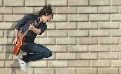 Fototapeta na wymiar Portrait of a Musician Jumping while Playing an Electric Guitar