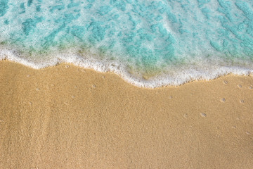 Fototapeta na wymiar Soft blue waves with foam of ocean on the sandy beach background.