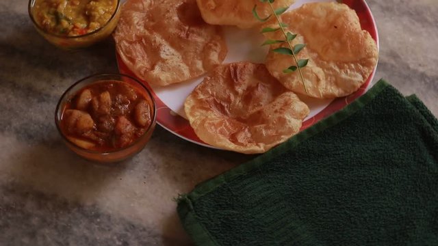rotation Chole Bhature or Chick pea curry and Fried Puri served in terracotta crockery over nice background.