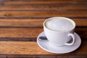 cup of hot green tea mucha on wood table.