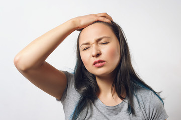 young girl grabs her head with her hand and depicts a severe headache. On white background