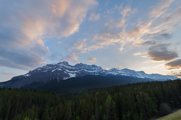 partially cloudy sunset over mountains and forest