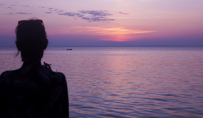 Fototapeta premium Woman was looking at the boat on the beach at sunset