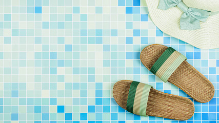 Sandals and a beach hat on blue ceramic tiles at the pool. - Summer holiday concept.