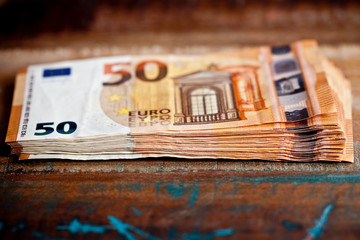 Pile of fifty euro banknotes. Currency notes stacked on wooden table.