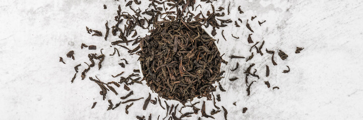 Dried tea is poured into a white ceramic cup on a marble table. View from above. Layout.