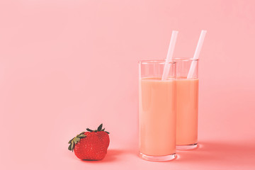 Two glasses with strawberry milk on pink background