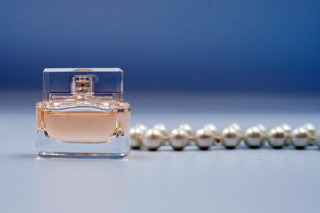 perfume bottle and white beads on blue background