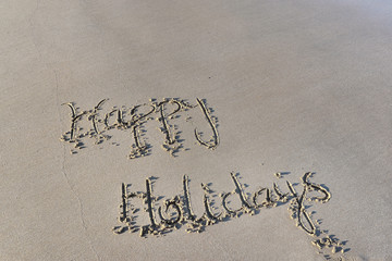 happy holidays written on the wet  sand at low tide