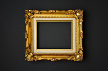 gold vintage picture frame on black color wall background, copy space, funeral and mourning concept