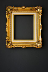 gold vintage picture frame on black color wall background, copy space, funeral and mourning concept