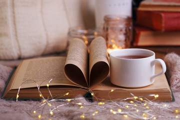 Hot tea and book with woolan plaid on wood background - seasonal relax concept. Autumn winter weekend still life background, cozy himely hygge leisure