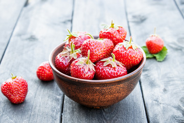 Fresh strawberries in a bowl on a wooden table.