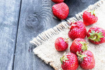 ripe red strawberries scattered on a table on burlap.