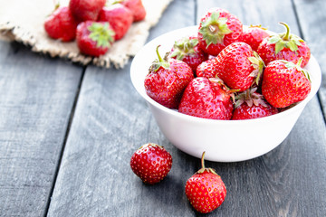 bowl full of fresh strawberries on wooden background.