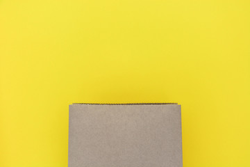 mock up of blank brown paper shopping bag isolated yellow background, copy space, top view, flat lay