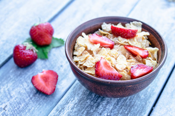 Fresh homemade muesli, muesli with strawberries in a plate on a blue background