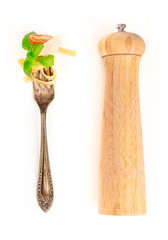 Italian pasta design elements. A fork with pappardelle, basil, cheese, and tomato, shot from above on a white background with a pepper mill and copy space