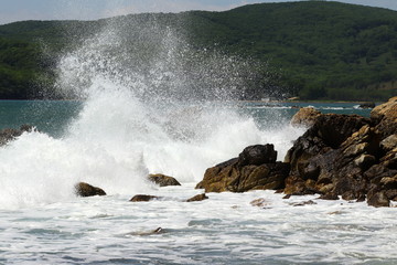 Big storm waves hitting the coastal rocks of the sea. Sunny windy day, blue sky. Splashes and foam. Storm landscape.