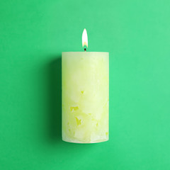 Alight scented wax candle on color background