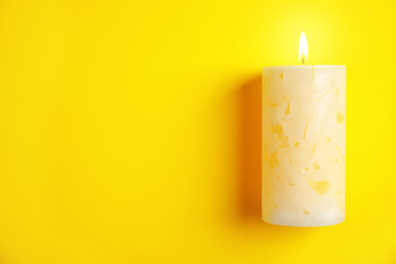 Alight wax candle and space for text on color background