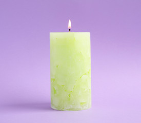 Alight scented wax candle on color background