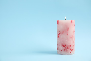 Alight wax candle on color background. Space for text