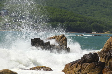Big storm waves hitting the coastal rocks of the sea. Sunny windy day, blue sky. Splashes and foam....