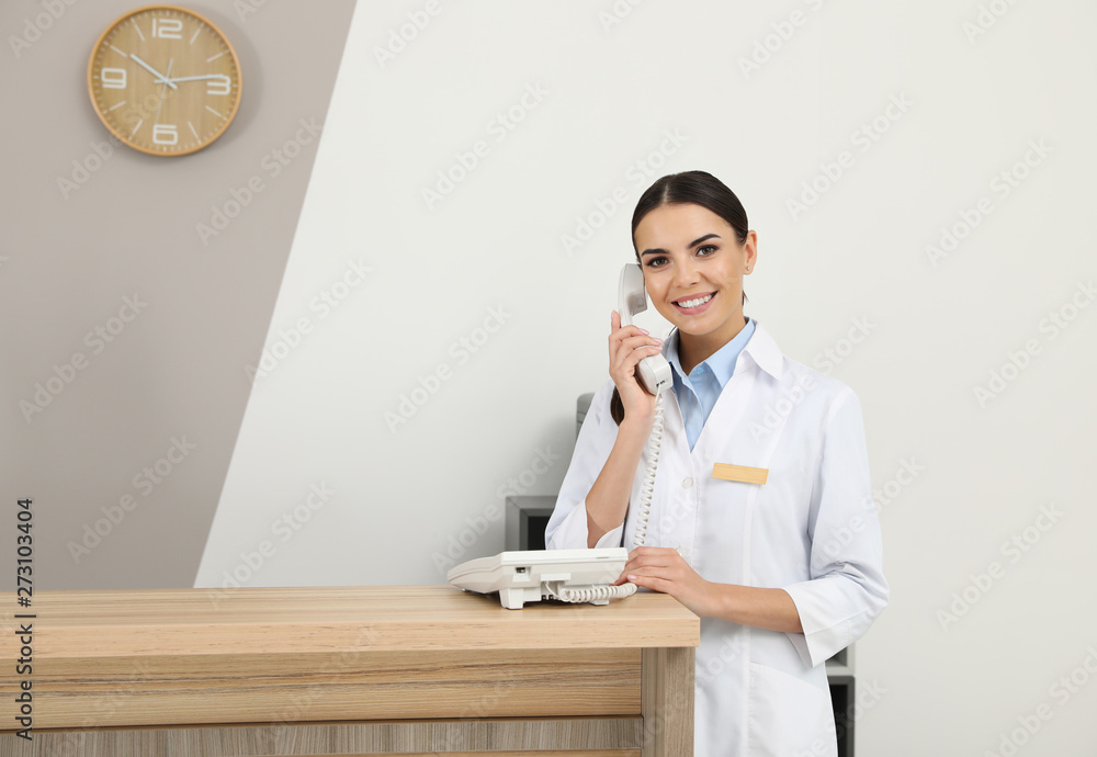 Wall mural Receptionist talking on telephone at desk in modern clinic