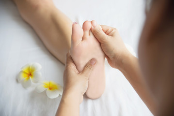 Obraz na płótnie Canvas Woman receiving foot massage service from masseuse close up at hand and foot - relax in foot massage therapy service concept