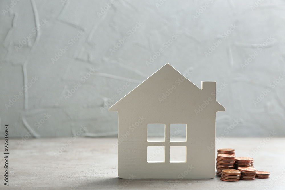 Wall mural House figure and coins on table against grey background. Space for text