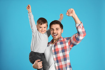 Portrait of emotional dad and his son on color background
